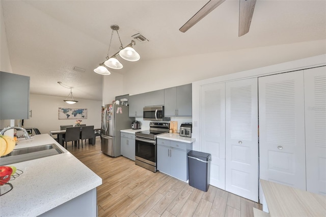 kitchen with decorative light fixtures, appliances with stainless steel finishes, sink, and lofted ceiling