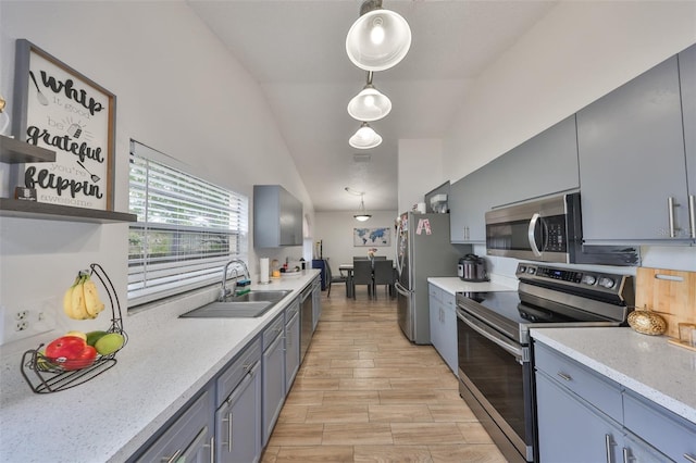 kitchen featuring light stone countertops, appliances with stainless steel finishes, lofted ceiling, sink, and hanging light fixtures