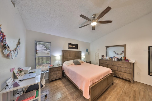 bedroom with ceiling fan, a textured ceiling, lofted ceiling, and light wood-type flooring