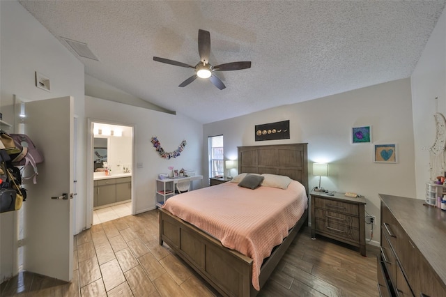 bedroom with vaulted ceiling, ceiling fan, a textured ceiling, and ensuite bath