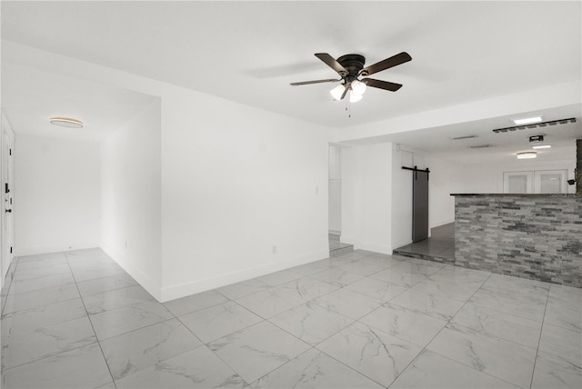 unfurnished room with a barn door and ceiling fan