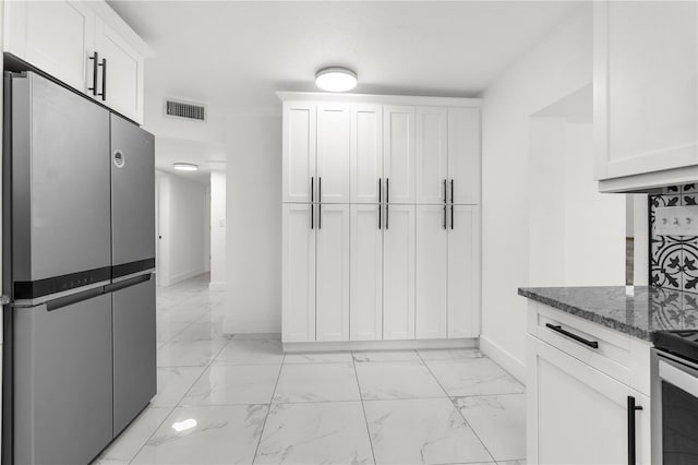 kitchen with dark stone counters, white cabinets, and appliances with stainless steel finishes