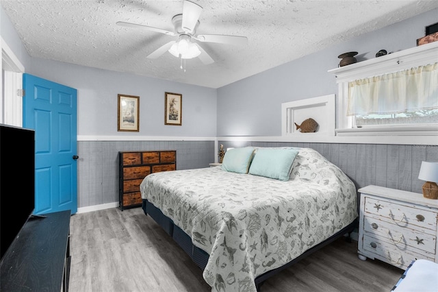 bedroom featuring ceiling fan, hardwood / wood-style floors, and a textured ceiling