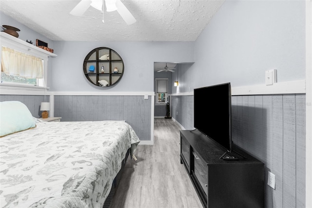 bedroom with ceiling fan, light hardwood / wood-style flooring, and a textured ceiling