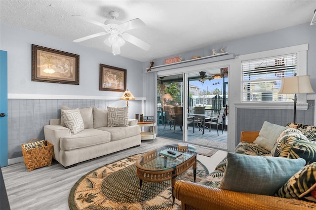 living room featuring a textured ceiling, light hardwood / wood-style flooring, and ceiling fan