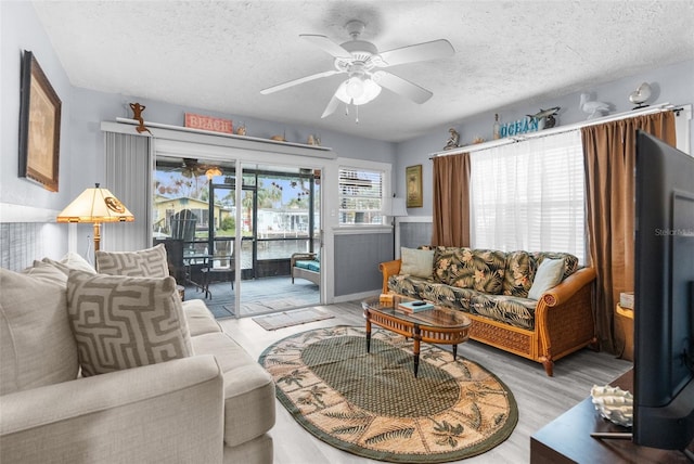 living room featuring ceiling fan, a textured ceiling, and light hardwood / wood-style flooring