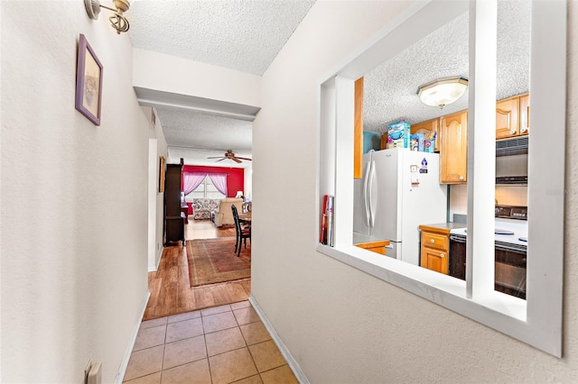 hallway with a textured ceiling and light tile patterned floors