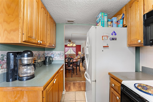 kitchen with ceiling fan, a textured ceiling, light tile patterned floors, and white fridge