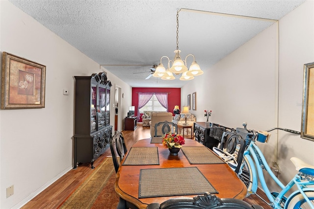 dining area with a textured ceiling, ceiling fan with notable chandelier, and hardwood / wood-style floors