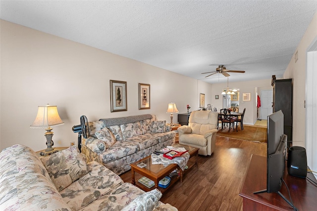 living room with dark wood-type flooring, ceiling fan, and a textured ceiling