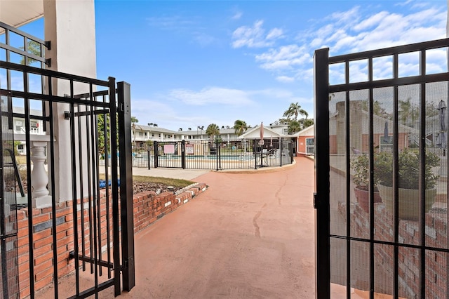 view of gate with fence and a community pool