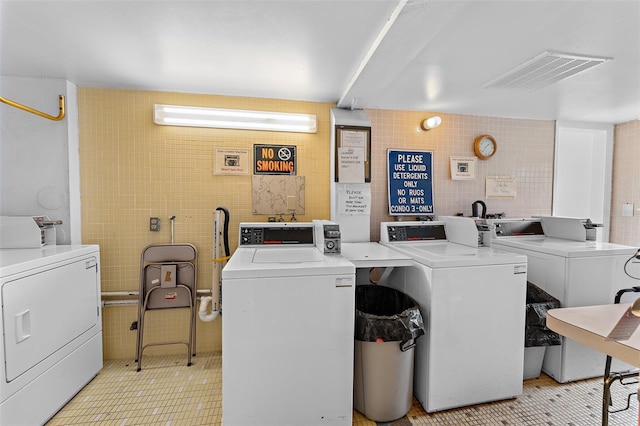 clothes washing area with washer and dryer and tile walls