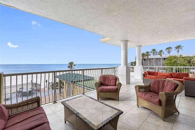 balcony featuring a view of the beach, a water view, and an outdoor hangout area