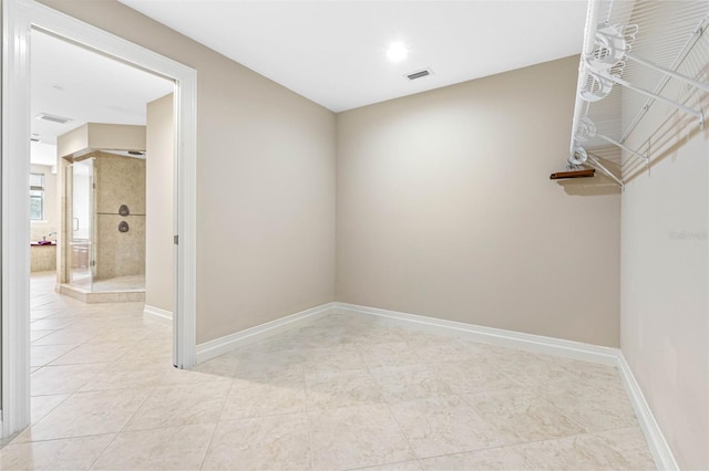 spare room featuring light tile patterned flooring, visible vents, and baseboards