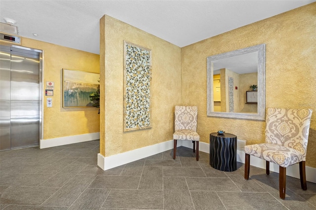 living area with baseboards and elevator