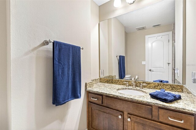 bathroom featuring toilet, vanity, and visible vents