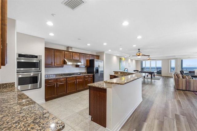 kitchen featuring recessed lighting, under cabinet range hood, visible vents, appliances with stainless steel finishes, and dark stone counters