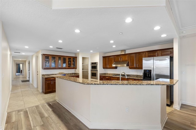 kitchen with stainless steel appliances, recessed lighting, a large island with sink, and under cabinet range hood