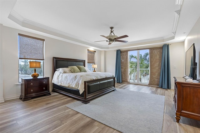 bedroom with light wood-style floors, a tray ceiling, and ornamental molding