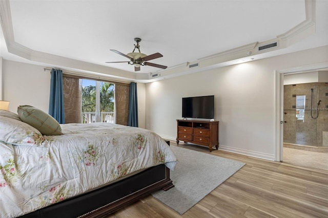 bedroom featuring baseboards, visible vents, connected bathroom, a tray ceiling, and light wood-style floors