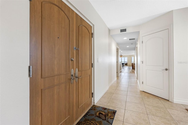 hall with visible vents, baseboards, and light tile patterned floors