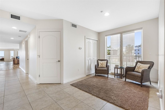 living area featuring light tile patterned floors, visible vents, and baseboards