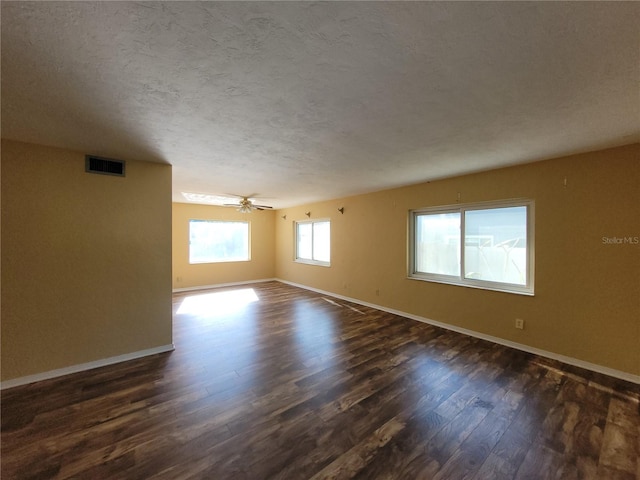 unfurnished room with ceiling fan, plenty of natural light, dark hardwood / wood-style floors, and a textured ceiling