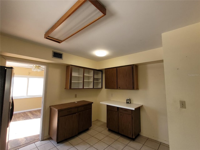 kitchen featuring dark brown cabinetry, stainless steel refrigerator, ceiling fan, and light tile patterned flooring