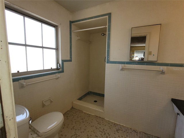 bathroom featuring tile patterned flooring, a tile shower, tile walls, and toilet