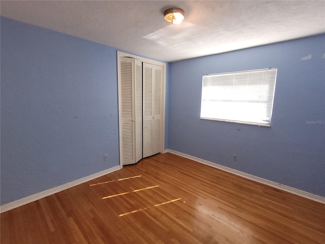 unfurnished bedroom featuring wood-type flooring and a closet