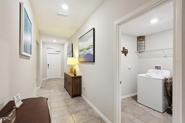 hallway featuring washer / dryer and light tile patterned floors