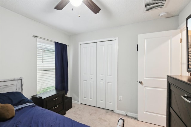 carpeted bedroom featuring ceiling fan, multiple windows, a closet, and a textured ceiling