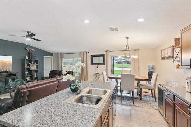 kitchen with sink, a wealth of natural light, hanging light fixtures, and a center island with sink