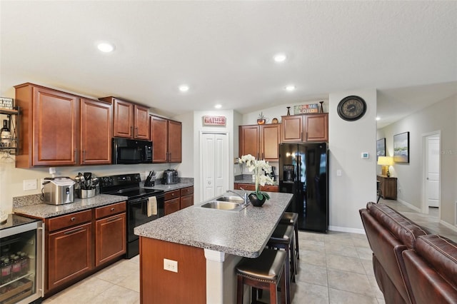 kitchen with wine cooler, sink, a kitchen bar, a kitchen island with sink, and black appliances