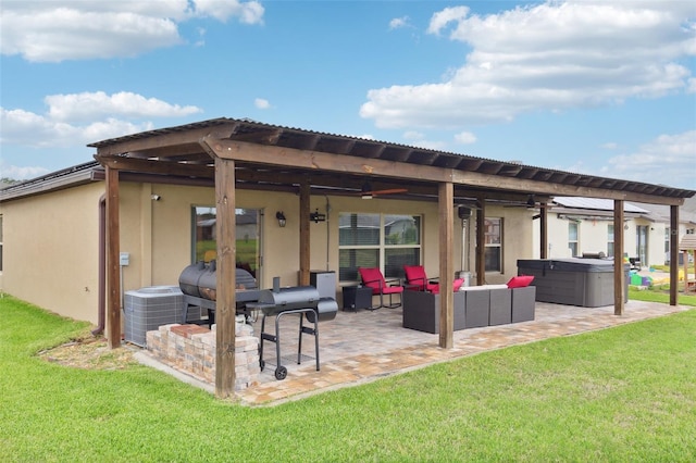 rear view of property featuring outdoor lounge area, a patio area, a lawn, and a hot tub