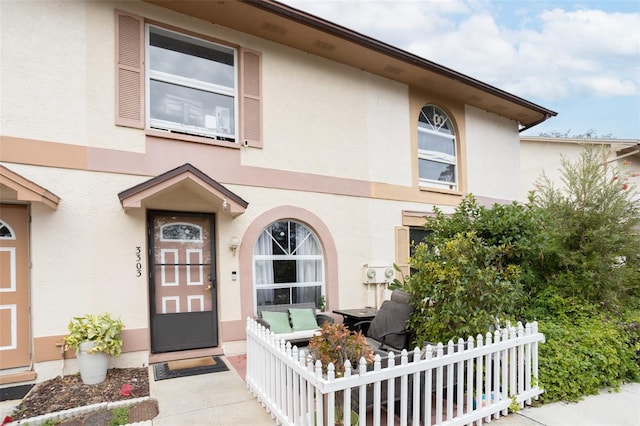 view of exterior entry featuring fence and stucco siding