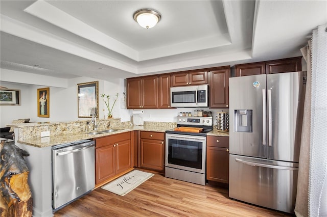 kitchen featuring light stone counters, sink, a raised ceiling, and stainless steel appliances