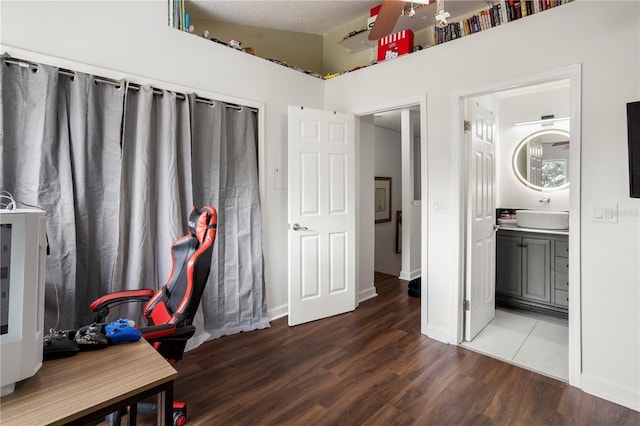 interior space featuring lofted ceiling, hardwood / wood-style floors, ensuite bath, sink, and a textured ceiling