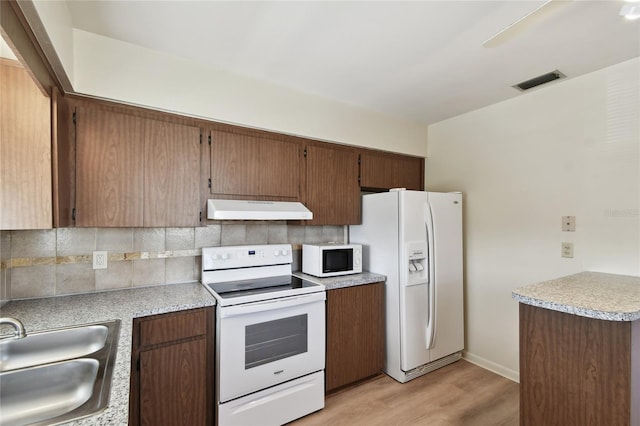 kitchen with sink, white appliances, light hardwood / wood-style flooring, and decorative backsplash