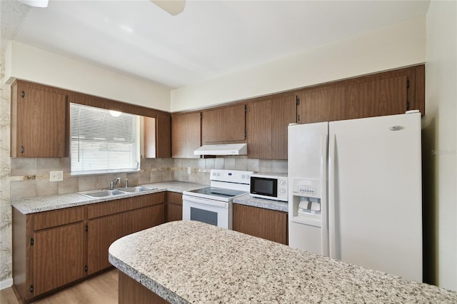 kitchen featuring sink, white appliances, tasteful backsplash, and light hardwood / wood-style flooring