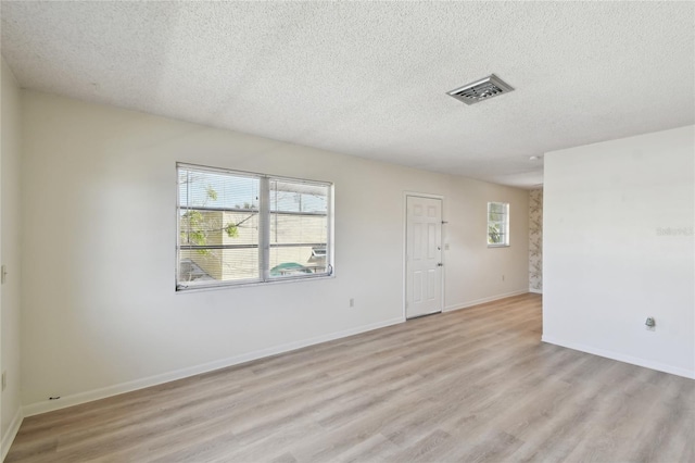 spare room featuring light hardwood / wood-style flooring and a textured ceiling