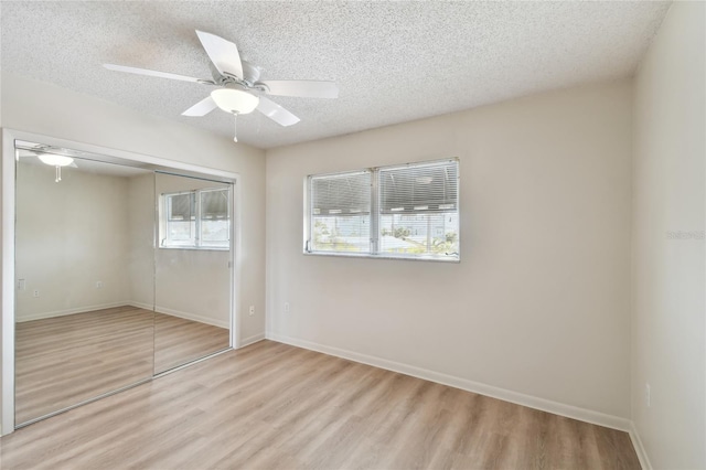 unfurnished bedroom featuring ceiling fan, light hardwood / wood-style floors, a textured ceiling, and a closet