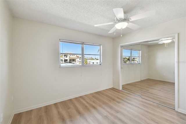 unfurnished bedroom with light wood-type flooring, a textured ceiling, a closet, and ceiling fan