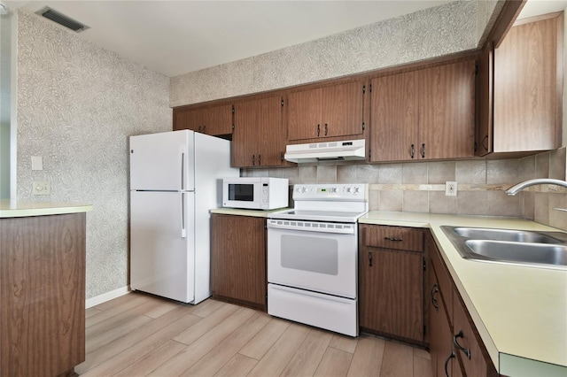 kitchen featuring light hardwood / wood-style floors, sink, white appliances, and backsplash