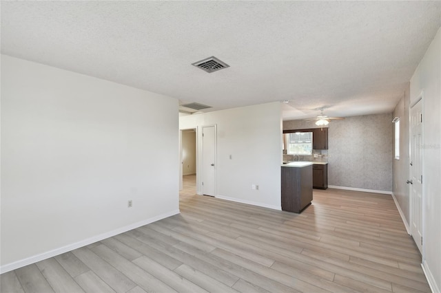 unfurnished living room featuring ceiling fan, a textured ceiling, and light hardwood / wood-style flooring