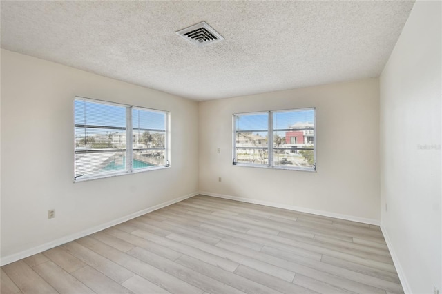 unfurnished room with light wood-type flooring and a textured ceiling