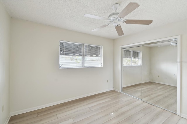 unfurnished bedroom featuring ceiling fan, light hardwood / wood-style floors, a textured ceiling, and a closet