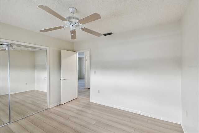 unfurnished bedroom featuring a closet, ceiling fan, light hardwood / wood-style flooring, and a textured ceiling