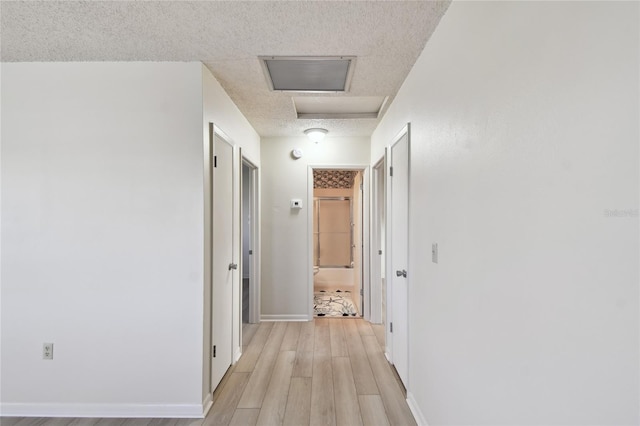 hallway featuring a textured ceiling and light wood-type flooring