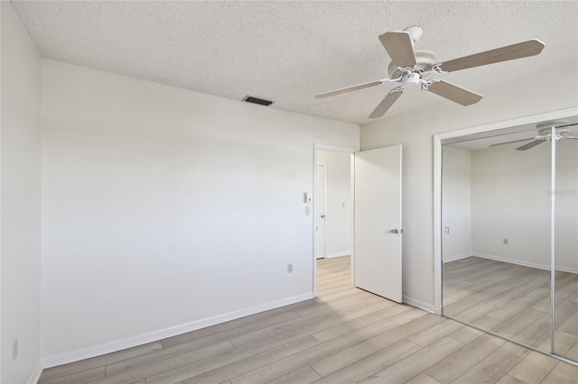 unfurnished bedroom featuring ceiling fan, light hardwood / wood-style floors, a textured ceiling, and a closet